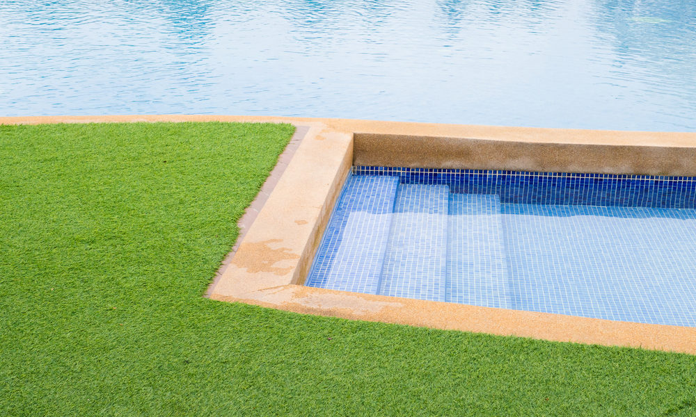 Backyard pool and jacuzzi with artificial grass.
