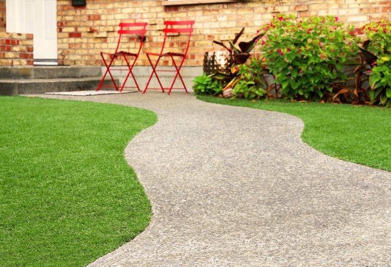 A walkway leading up to a house surrounded by artificial grass.