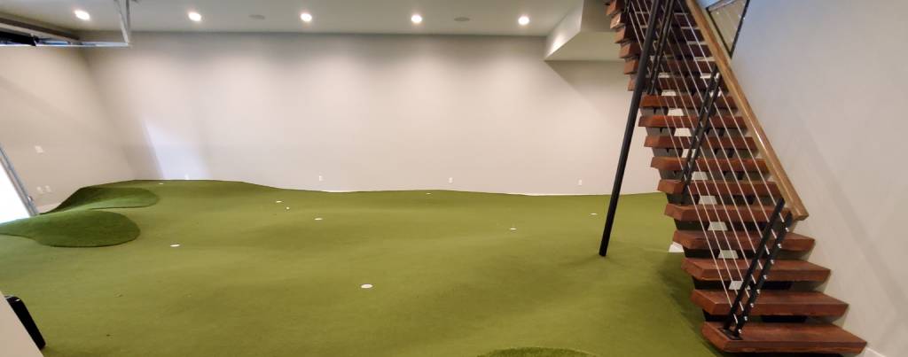 Residential artificial indoor putting green by stairs