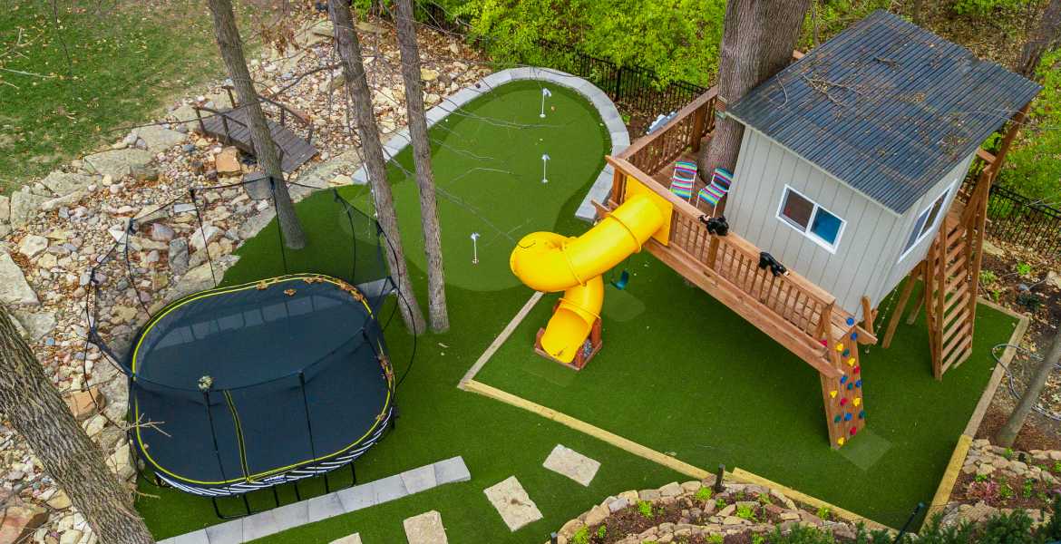 Yellow slide with artificial backyard playground grass